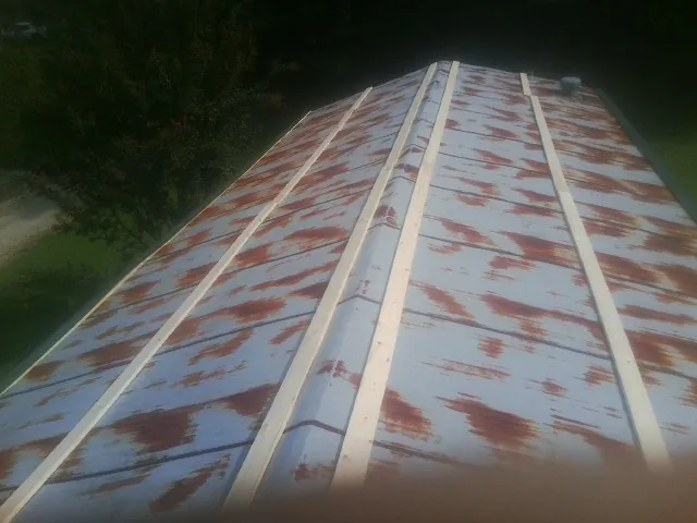 Rusted metal roof panels with new wood purlins before replacement — Storm Damage Roof Repair in Starr by Roofing Brothers