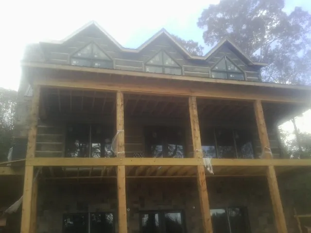 Dormers and porch framing on a large log home under construction — Roof Coating work by our crew in Starr