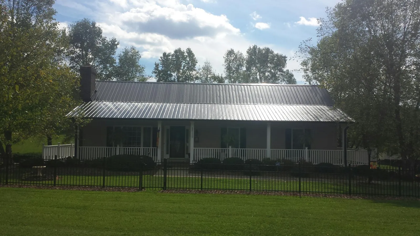 Gray metal roof on a brick ranch with a full width front porch — Gutter Guard Installation work by our crew in Starr